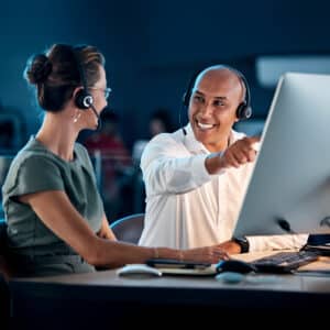 Call center, customer service and contact us, training and team leader help coworker, crm and communication at computer with headphone. Telemarketing, man and woman working together, support and call.