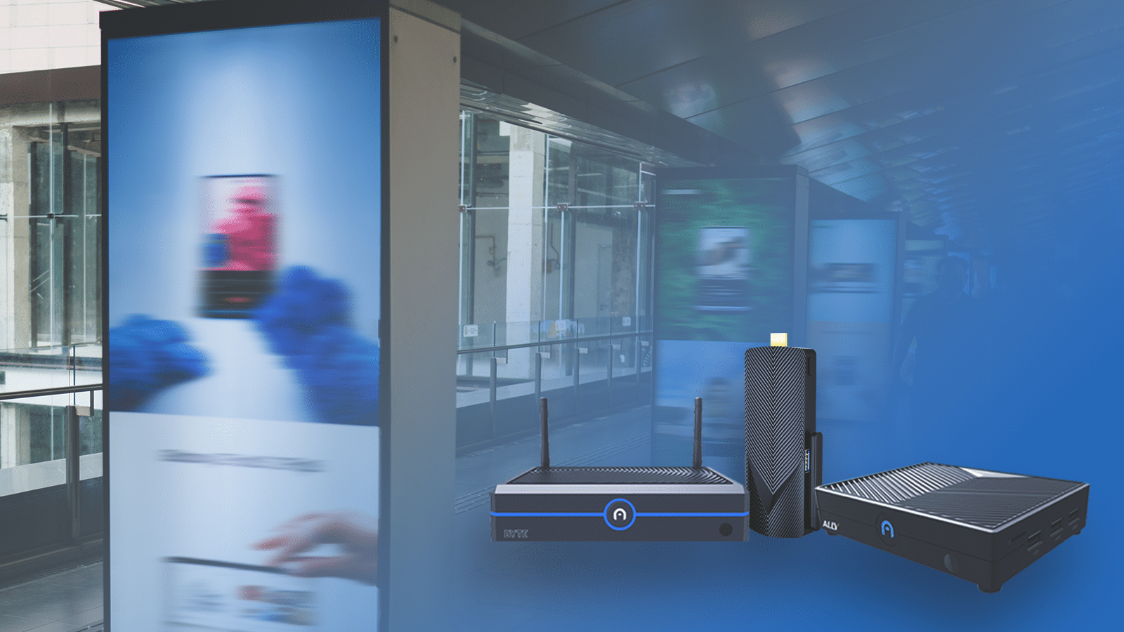 Image showing three mini PCs in the foreground: a router, a streaming device, and a modem. The background features a blurred indoor corridor with posters and digital signage advertising various products.