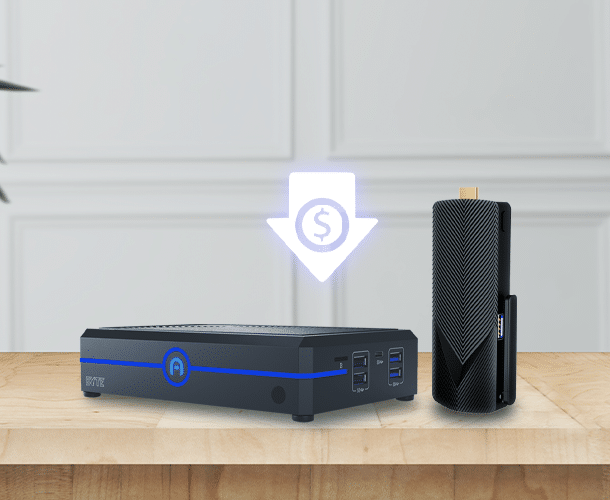 A small black computer and a compact black device are displayed on a wooden surface, with a glowing down arrow and dollar symbol above them, indicating reduced cost.